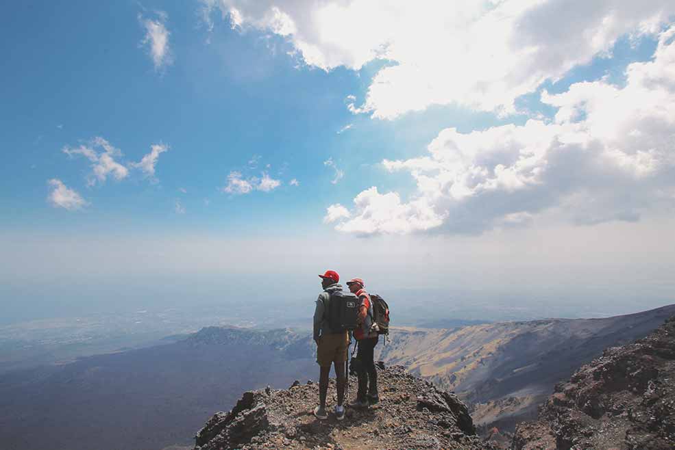 Mount Etna, Sicily two trekkers standing atop the volcanic range.